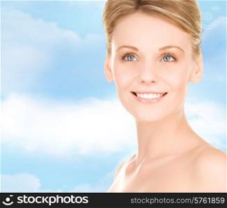 people, beauty and health care concept - close up of smiling young woman over blue sky background