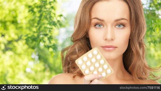 people, beauty and medicine care concept - beautiful woman with pills over green natural background. beautiful woman with medicine pills