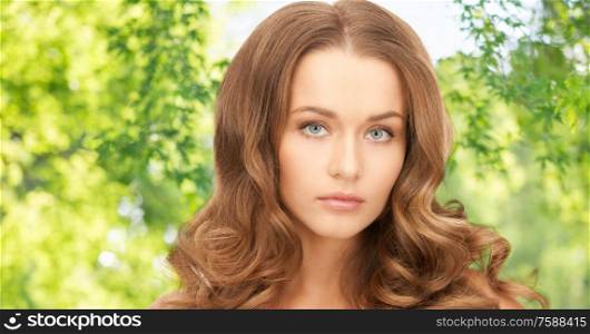 people, beauty and skin care concept - beautiful woman with curly hair over green natural background. beautiful woman with curly hair