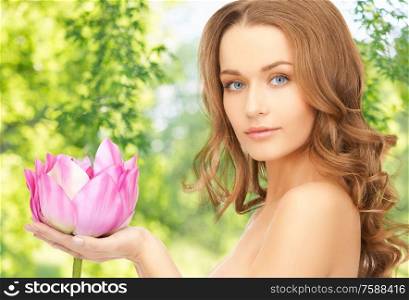 people, beauty and skin care concept - beautiful woman with pink lotus flower over green natural background. beautiful woman with pink lotus flower