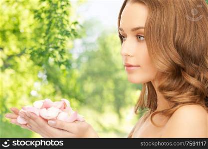 people, beauty and skin care concept - beautiful woman with rose flower petals over green natural background. beautiful woman with rose flower petals