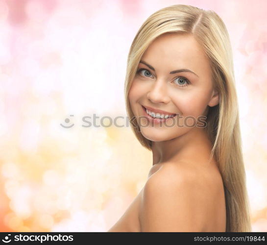 people, beauty, body and skin care concept - beautiful woman face and hands over yellow lights background