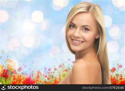 people, beauty, body and skin care concept - beautiful woman face and hands over poppy field and blue lights background