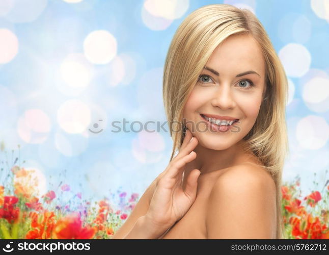 people, beauty, body and skin care concept - beautiful woman face and hands over poppy field and blue lights background