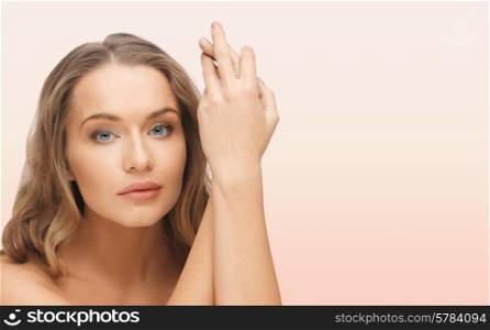 people, beauty, body and skin care concept - beautiful woman face and hands over pink background
