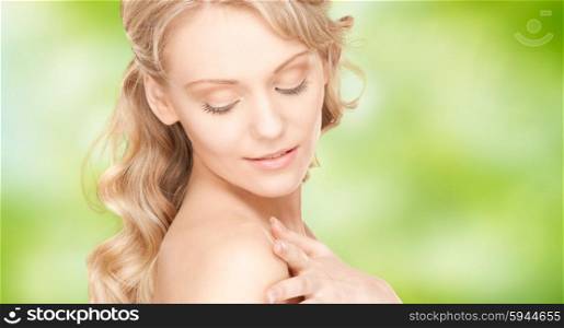 people, beauty, body and skin care concept - beautiful young happy woman with long hair over green natural background