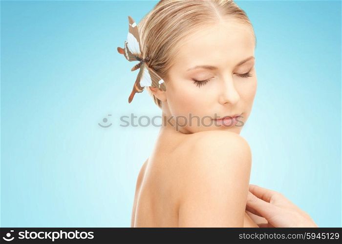 people, beauty, body and skin care concept - beautiful young happy woman with butterfly hairpin over blue background