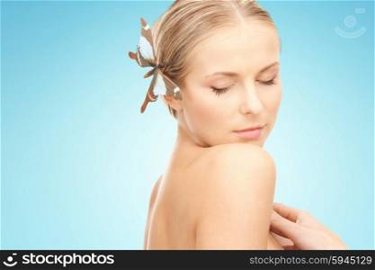 people, beauty, body and skin care concept - beautiful young happy woman with butterfly hairpin over blue background