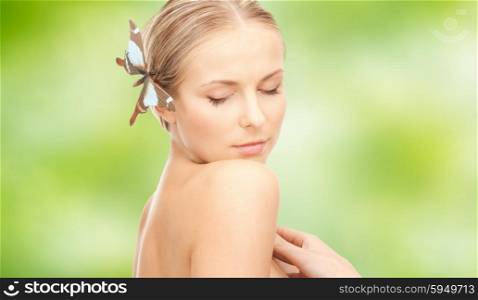 people, beauty, body and skin care concept - beautiful young happy woman with butterfly hairpin over green natural background