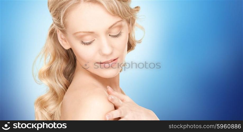 people, beauty, body and skin care concept - beautiful young happy woman with long hair over blue background