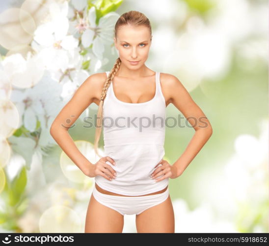 people, beauty, body care and health concept - happy beautiful young woman in cotton underwear over green cherry blossom background