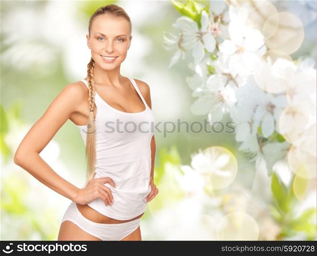 people, beauty, body care and health concept - happy beautiful young woman in cotton underwear over green cherry blossom background