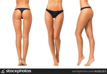 people, beauty, bodycare, underwear and slimming concept - female legs and bottom in black bikini panties over white background