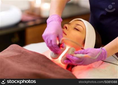 people, beauty, cosmetic treatment, cosmetology and technology concept - beautician with microdermabrasion device doing face exfoliation to young woman lying at spa. young woman having face microdermabrasion at spa