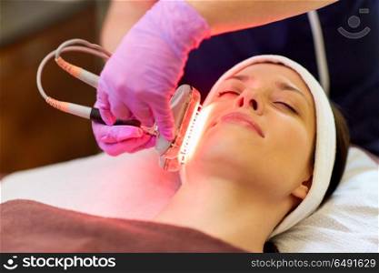 people, beauty, cosmetic treatment, cosmetology and technology concept - beautician with microdermabrasion device doing face exfoliation to young woman lying at spa. young woman having face microdermabrasion at spa. young woman having face microdermabrasion at spa