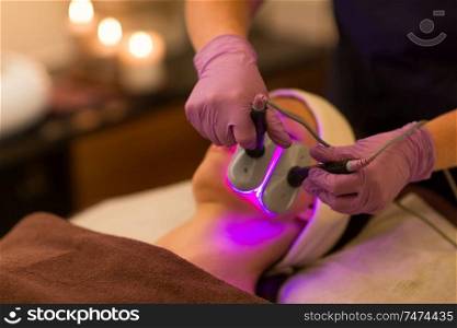 people, beauty, cosmetic treatment, cosmetology and technology concept - close up of beautician with microdermabrasion device doing face exfoliation to woman lying at spa. young woman having face microdermabrasion at spa