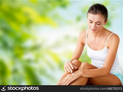 people, beauty, cosmetics and bodycare concept - beautiful woman applying moisturizing hand cream over green natural background. beautiful woman applying hand cream. beautiful woman applying hand cream