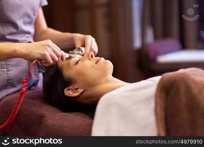 people, beauty, cosmetology and technology concept - beautiful young woman having needle free mesotherapy or hydradermie facial treatment by microcurrent firming device in spa. woman having hydradermie facial treatment in spa