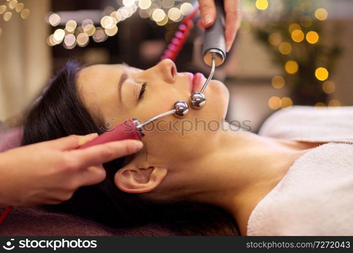 people, beauty, cosmetology and technology concept - beautiful young woman having needle free mesotherapy or hydradermie facial treatment by microcurrent firming device in spa. woman having hydradermie facial treatment in spa