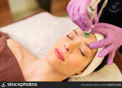 people, beauty, cosmetology, exfoliation and technology concept - beautiful young woman having microdermabrasion facial treatment with crystals in spa. woman having microdermabrasion facial treatment