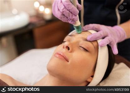 people, beauty, cosmetology, exfoliation and technology concept - beautiful young woman having microdermabrasion facial treatment with crystals in spa. woman having microdermabrasion facial treatment