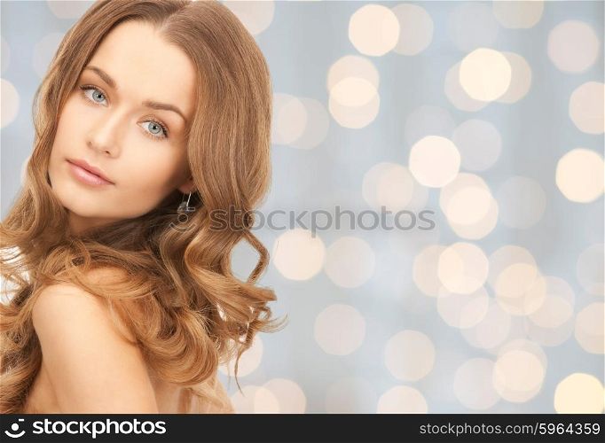 people, beauty, hair and skin care concept - beautiful woman with curly hairstyle over holidays lights background