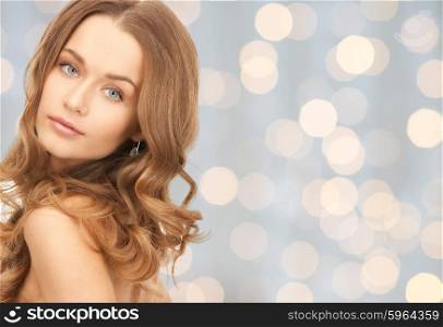 people, beauty, hair and skin care concept - beautiful woman with curly hairstyle over holidays lights background