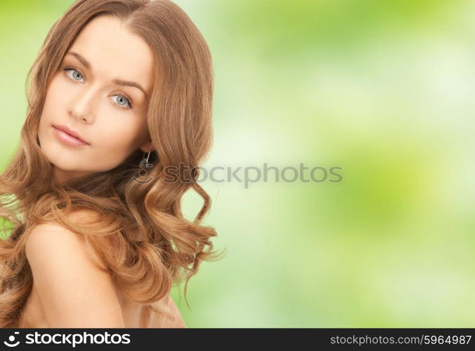 people, beauty, hair and skin care concept - beautiful woman with curly hairstyle over green natural background