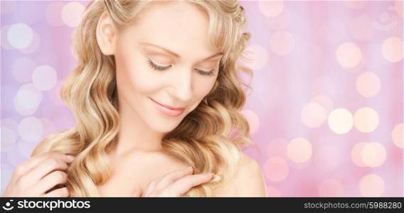 people, beauty, hair and skin care concept - beautiful woman with curly hairstyle over pink holidays lights background