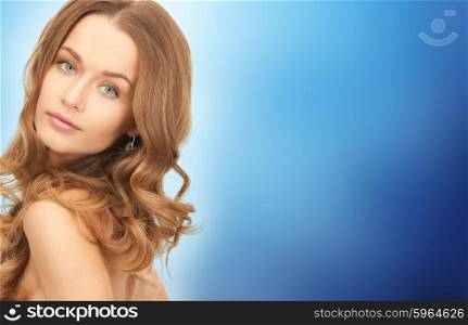 people, beauty, hair and skin care concept - beautiful woman with curly hairstyle over blue background