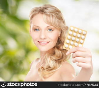 people, beauty, healthcare and medicine concept - happy young woman holding package of pills over green background