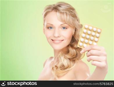 people, beauty, healthcare and medicine concept - happy young woman holding package of pills over green background