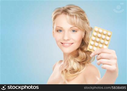 people, beauty, healthcare and medicine concept - happy young woman holding package of pills over blue background