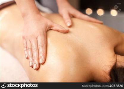 people, beauty, healthy lifestyle and relaxation concept - beautiful young woman lying and having back massage at spa. woman lying and having back massage at spa
