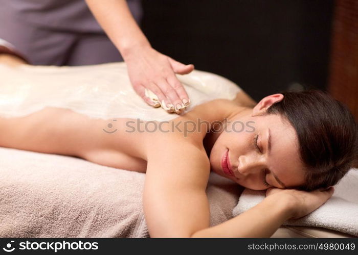 people, beauty, healthy lifestyle and relaxation concept - beautiful young woman lying and having back massage with cream at spa. woman lying and having back massage at spa