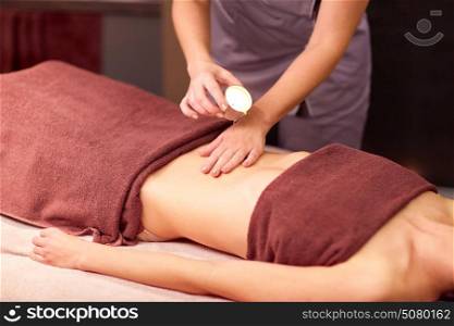 people, beauty, healthy lifestyle and relaxation concept - beautiful young woman lying and having massage with hot oil at spa. woman lying and having massage with hot oil at spa