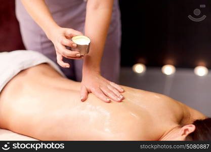 people, beauty, healthy lifestyle and relaxation concept - beautiful young woman lying and having back massage with hot oil at spa. woman lying and having back massage at spa