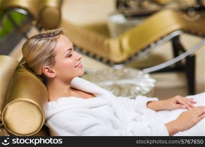 people, beauty, healthy lifestyle and relaxation concept - beautiful young woman lying on chaise-longue in bath robe at spa