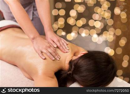 people, beauty, healthy lifestyle and relaxation concept - beautiful young woman lying and having back massage at spa parlor. woman lying and having back massage at spa parlor
