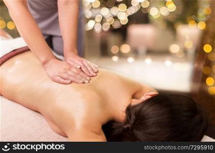 people, beauty, healthy lifestyle and relaxation concept - beautiful young woman lying and having back massage at spa parlor. woman lying and having back massage at spa parlor