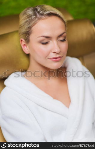 people, beauty, healthy lifestyle and relaxation concept - close up of beautiful young woman resting on chair in bath robe at spa