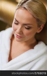 people, beauty, healthy lifestyle and relaxation concept - close up of beautiful young woman resting on chair in bath robe at spa