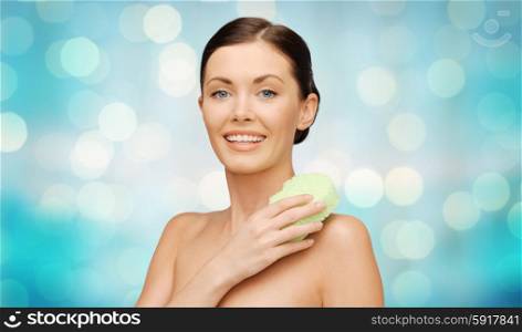 people, beauty, hygiene and summer concept - beautiful woman with sponge over blue holidays lights