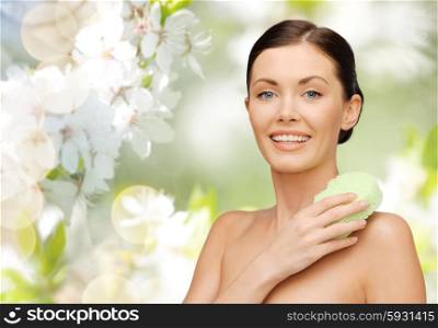 people, beauty, hygiene and summer concept - beautiful woman with sponge over cherry blossom background