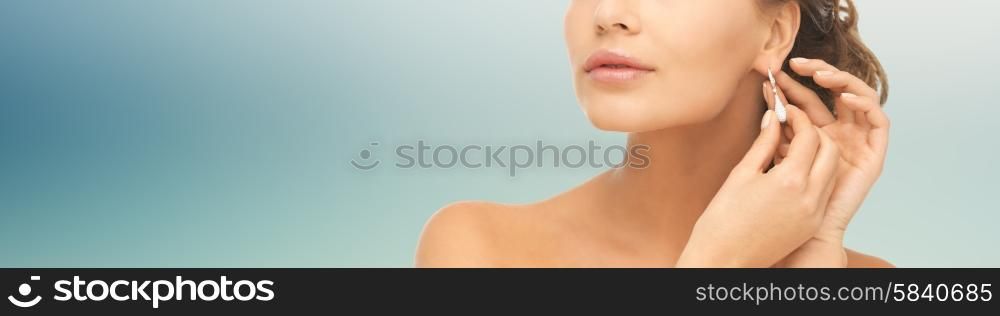 people, beauty, jewelry and accessories concept - beautiful woman with diamond earrings over blue background