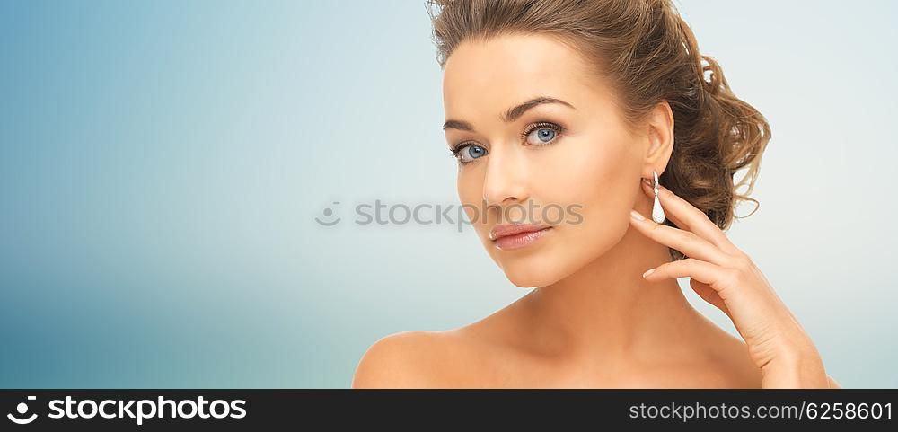 people, beauty, jewelry and accessories concept - beautiful woman with diamond earrings over blue background