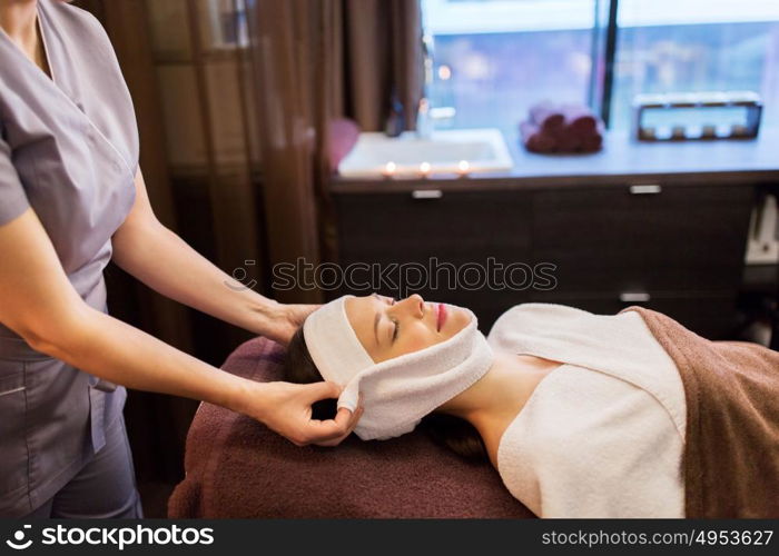 people, beauty, lifestyle and relaxation concept - beautiful young woman lying with closed eyes and having face massage with towel at spa parlor. woman having face massage with towel at spa parlor