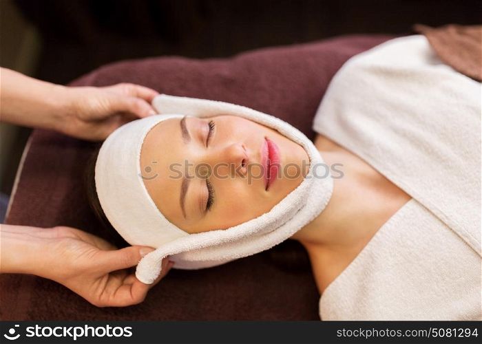 people, beauty, lifestyle and relaxation concept - beautiful young woman lying with closed eyes and having face massage with towel at spa. woman having face massage with towel at spa