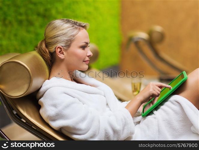 people, beauty, lifestyle, technology and relaxation concept - beautiful young woman in white bath robe with tablet pc computer social networking at spa
