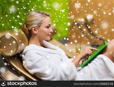 people, beauty, lifestyle, technology and relaxation concept - beautiful young woman in white bath robe with tablet pc computer social networking at spa with snow effect